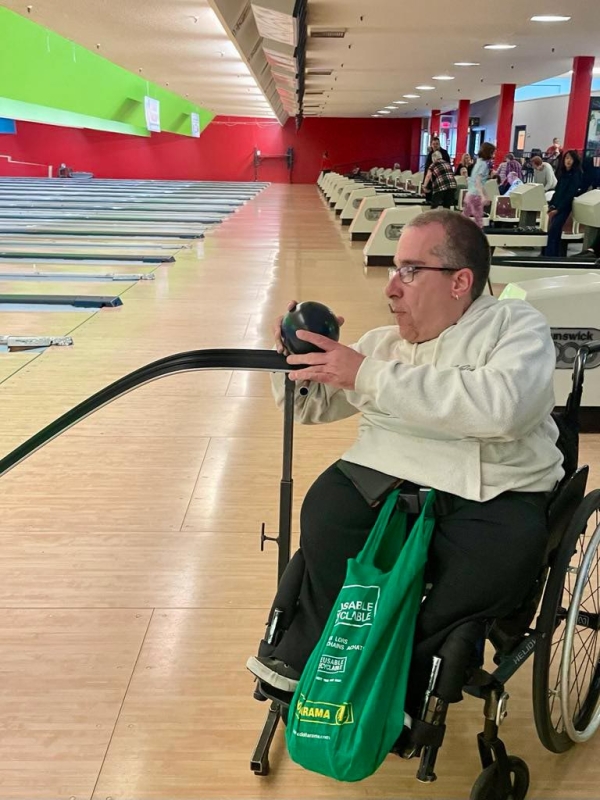 Un participant en fauteuil lance une boule de quille